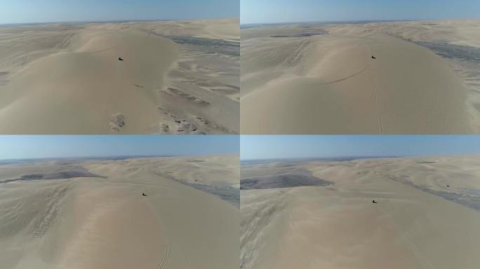 4x4车辆沿纳米比亚纳米布沙漠骨架海岸沙丘行驶的4k空中后视图