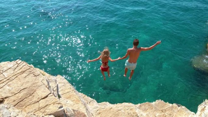 慢动作: 旅游夫妇决定跳下岩石悬崖，潜入大海。