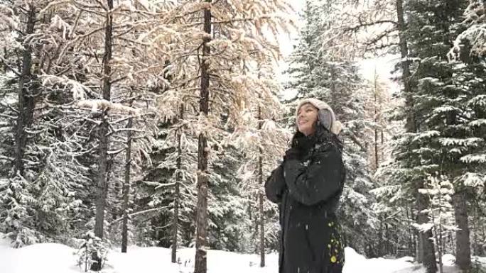 在冬季森林中享受降雪的亚洲妇女