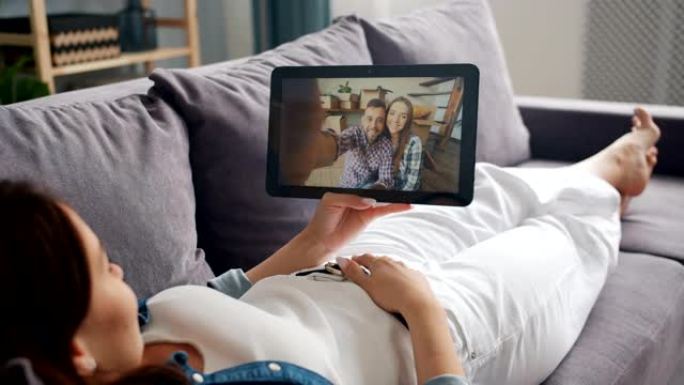 年轻女士与朋友在线聊天，在家用平板电脑进行视频通话