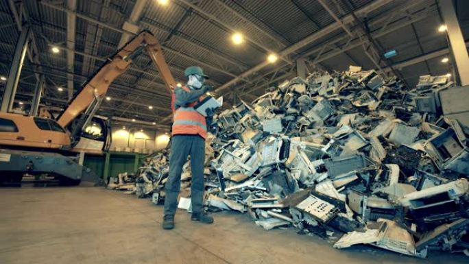 垃圾填埋场工作人员正在观察一堆破损的办公机器。回收工业，二手电子回收工厂。
