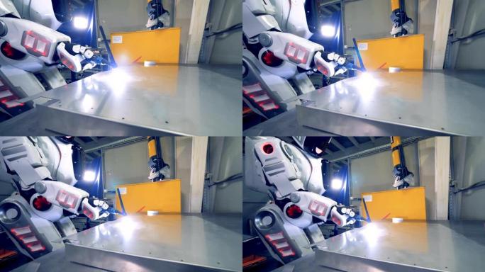 白色机器人使用焊接工具，特写。特殊机器人在工厂工作，焊接金属板。