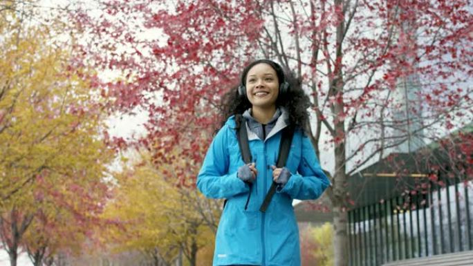 一个快乐的年轻女性在秋天走在一条小路上