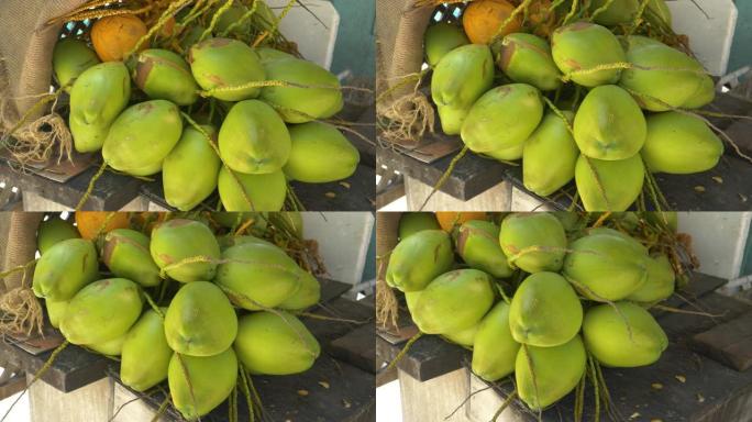 特写，dop: 木桌上摆满了成熟的绿色椰子的树枝。