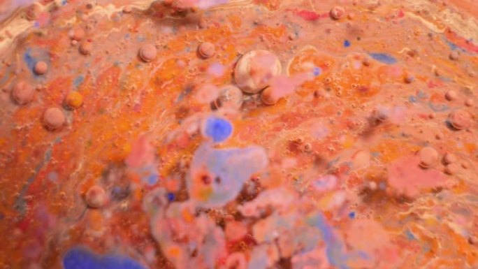 彩色丙烯酸涂料混合在美丽的图案中。珊瑚，橙色，红色和其他颜色的油墨水散布在表面并混合，创造出惊人的纹