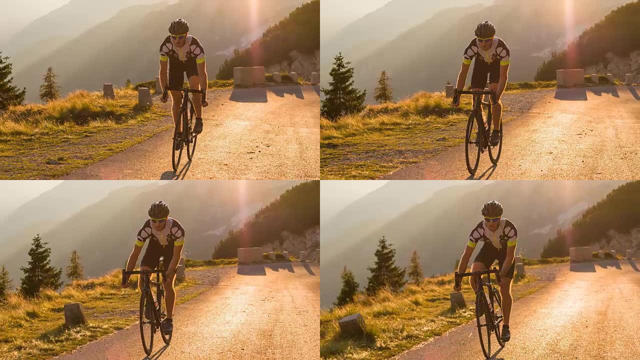 道路自行车手在日落时爬坡时站起来