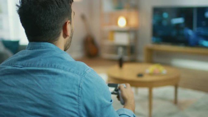 在客厅里，坐在沙发上的男人拿着控制器在游戏机视频游戏中玩耍，电视屏幕上显示了3D动作射击游戏。