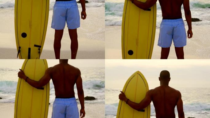 非洲裔美国男性冲浪者站在沙滩上的冲浪板后视图4k