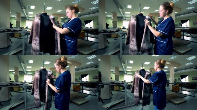 裁缝师正在刷挂在人体模型上的皮大衣