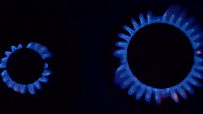 两个炊具燃烧器燃烧着蓝色的气体火焰。在黑色背景上拍摄的慢动作。