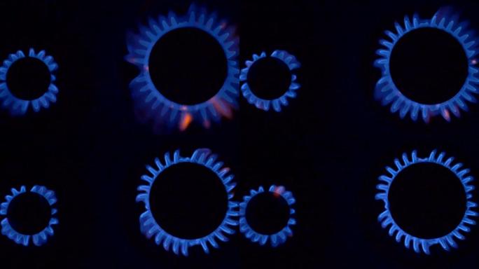两个炊具燃烧器燃烧着蓝色的气体火焰。在黑色背景上拍摄的慢动作。