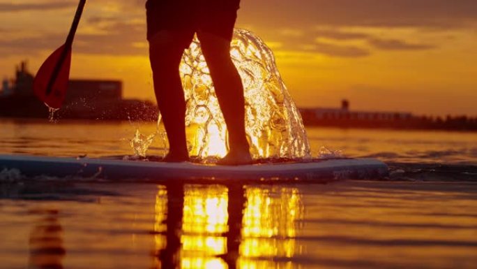 站立桨板运动员用桨叶泼水的超级SLO MO剪影