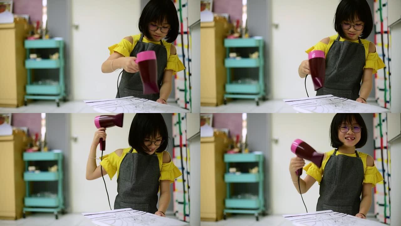 一名亚洲中国年轻女学生在美术课结束后用吹风机干掉水彩画