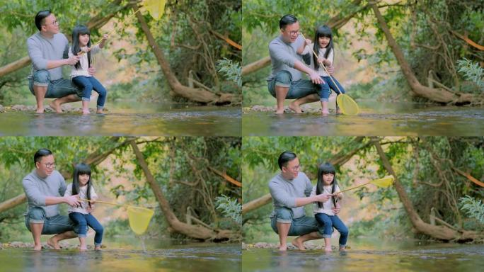 亚洲父亲在森林里教小女孩关于可持续性的知识。一个亚洲家庭带着渔网在水上行走。快乐的家庭在户外共度时光