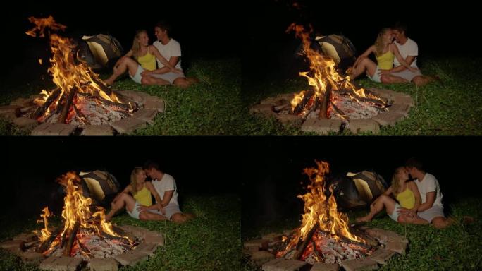 慢动作: 无忧无虑的情侣露营在篝火旁欢笑和亲吻。