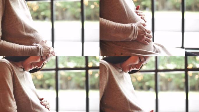 亚洲怀孕妇女温柔地抚摸和爱抚着她的肚子，爱她未来的婴儿和她生命中的每一刻