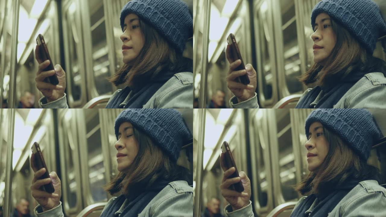 在纽约地铁上使用电话的亚洲妇女