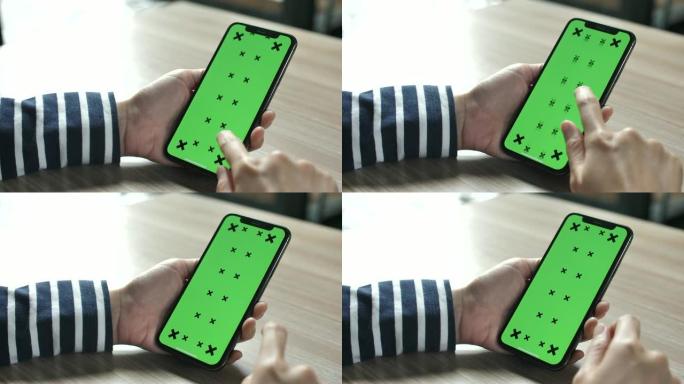 女人用手触摸绿色屏幕的智能手机