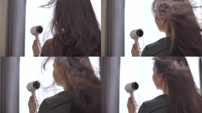 亚洲妇女用吹风机吹干头发