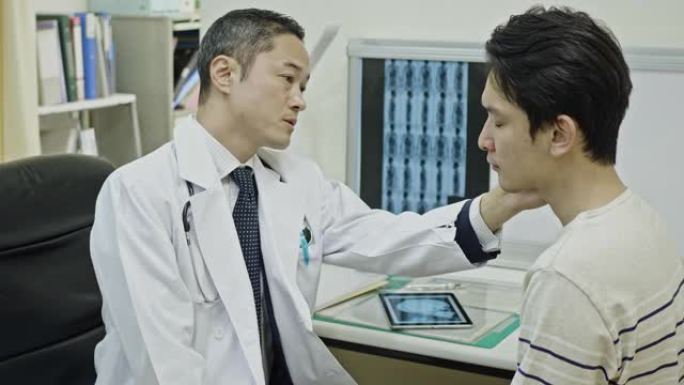 日本男性医生在医院检查患者的下巴