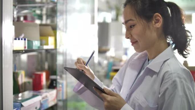 亚洲药剂师在药房中使用数字平板电脑