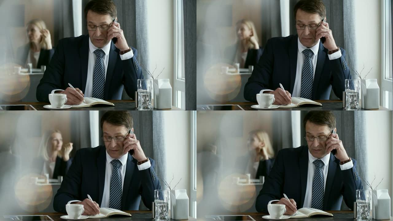 商人在电话上聊天并在咖啡桌旁做笔记