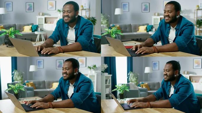 英俊微笑的黑人男子坐在舒适的客厅的桌子旁，用笔记本电脑。