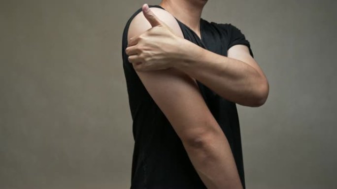 穿着黑色衬衫的亚洲男人感到肩膀疼痛。肌肉疼痛，保健概念。
