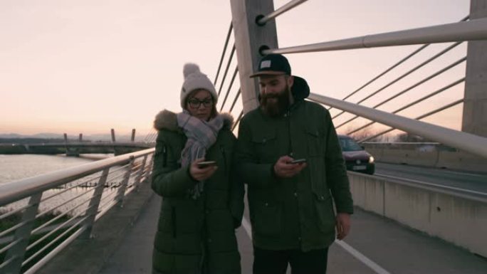 MS夫妇与智能手机在桥上行走和发短信