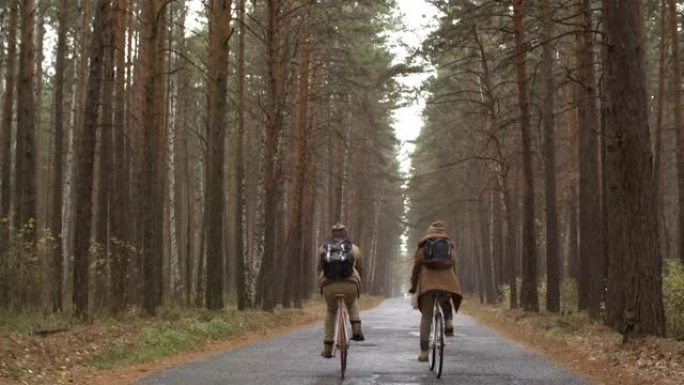 雨中夫妇骑自行车穿过森林的后视图