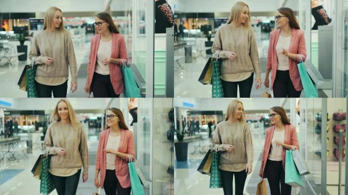 开朗的女人在商店购物中心里提着纸袋一起散步时说话和打手势。女孩们穿着时髦的服装和配饰。