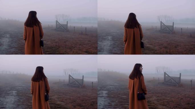 后视快乐美丽的高加索年轻女子冥想，沿着神秘的雾蒙蒙的晨间小路慢动作行走。