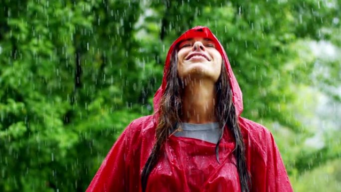 一个快乐的女人在雨中微笑，女人沉浸在快乐自由的雨中慢动作下的舞蹈中。