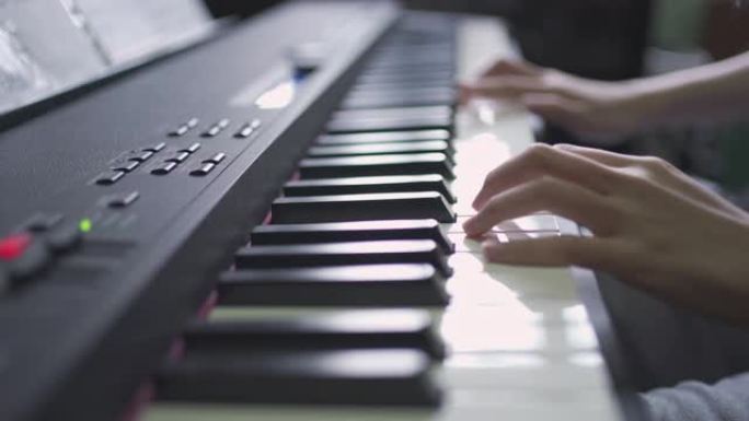 按下琴键的女孩的特写手指。女人的手在侧视图中独奏音乐