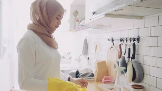 年轻的穆斯林妇女在家打扫厨房台面