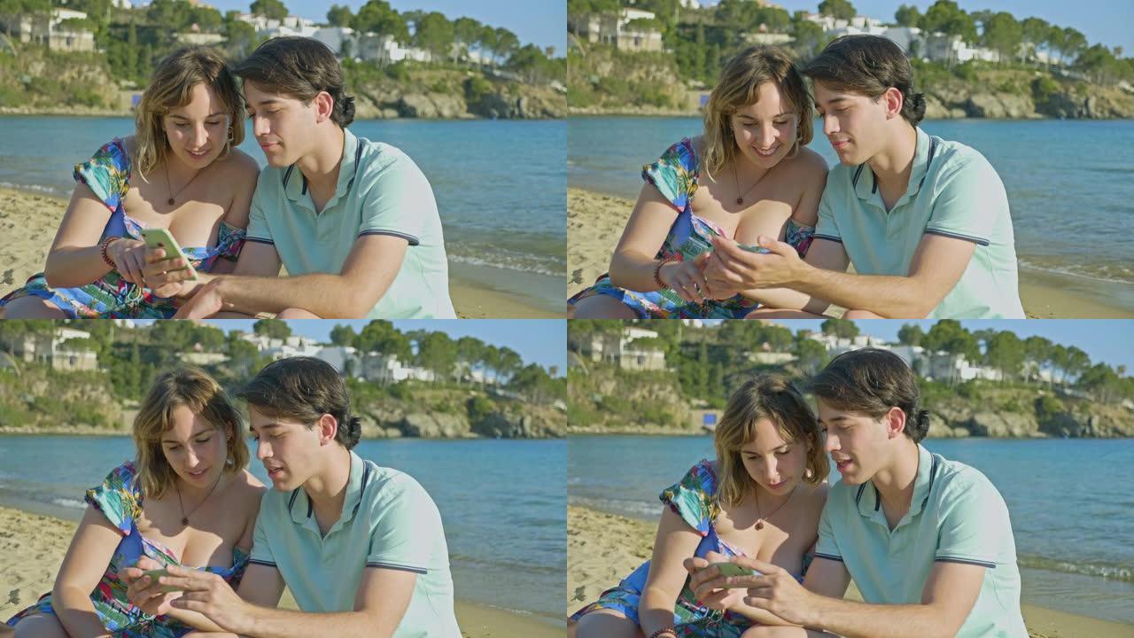 年轻夫妇在海滩看手机