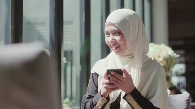 穆斯林妇女在咖啡店使用智能手机。