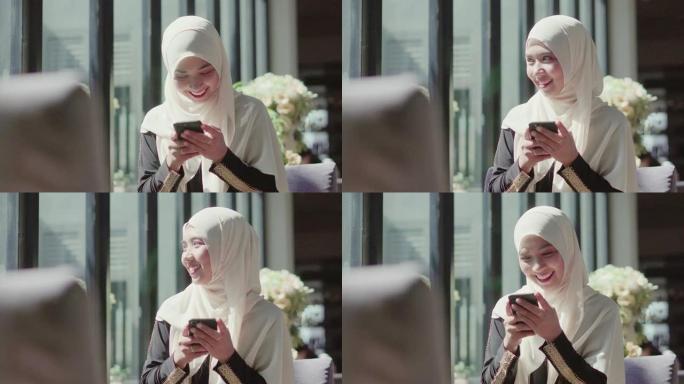 穆斯林妇女在咖啡店使用智能手机。