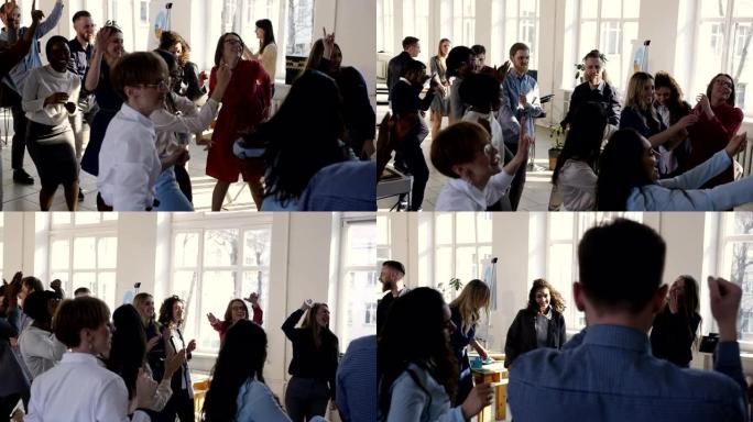 快乐的多民族商人团体在现代轻型办公室、工作场所聚会上一起跳舞庆祝节日。