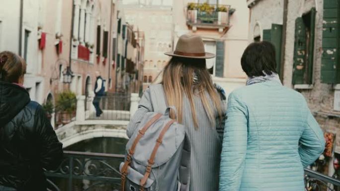 背景图年幼的女儿和年长的母亲一起站在运河大桥上，享受意大利威尼斯度假的景色。