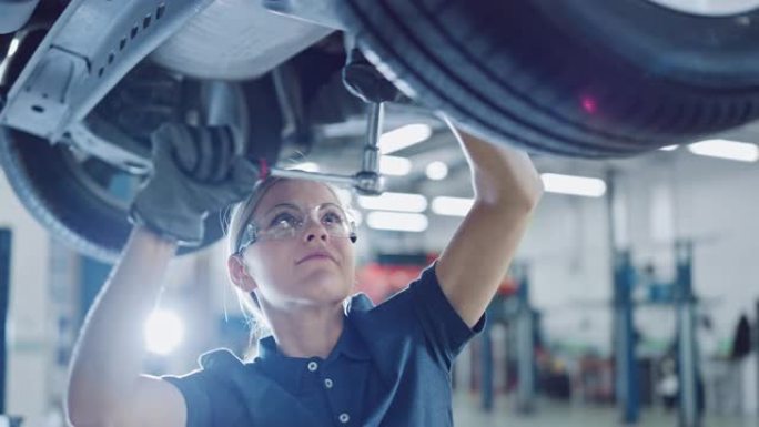 一个女机修工在一辆汽车上工作的慢动作肖像镜头。授权女性戴手套和使用棘轮下的汽车。现代洁净车间。