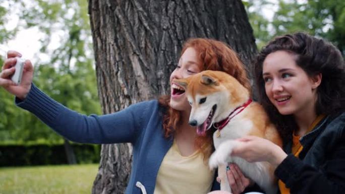 学生使用智能手机摄像头在公园与小狗自拍的慢动作