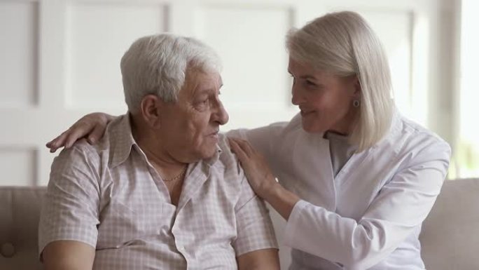 成熟的女性护士与老人交谈帮助解决问题