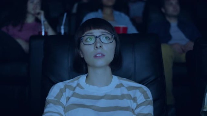 敏感的年轻女子在电影院里看着悲伤的表情有趣的戏剧