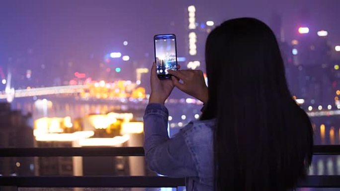 年轻女子为城市之夜拍照