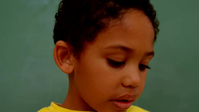 4k学校教室里非裔美国男生站在绿色黑板上的特写镜头