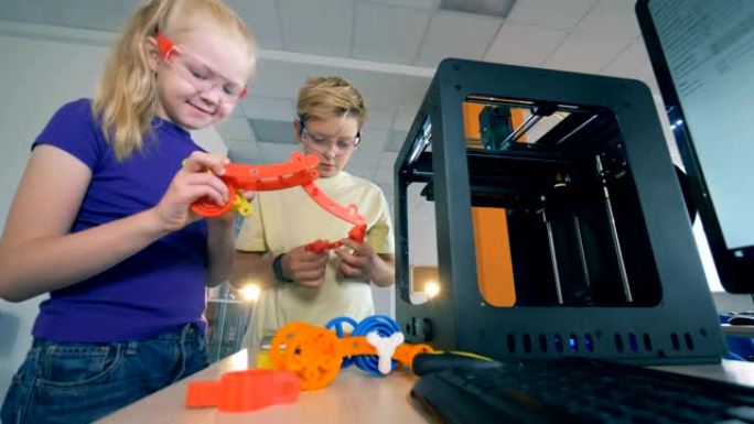 孩子们在学校实验室，使用3D打印模型。