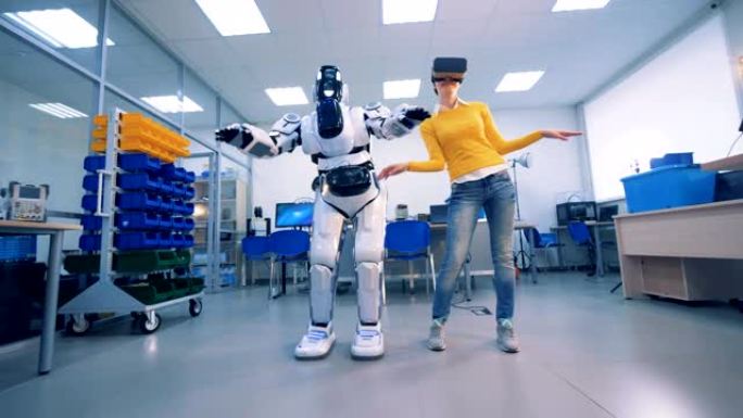 虚拟现实概念。戴VR眼镜的女性会跳舞，而机器人会复制它们。