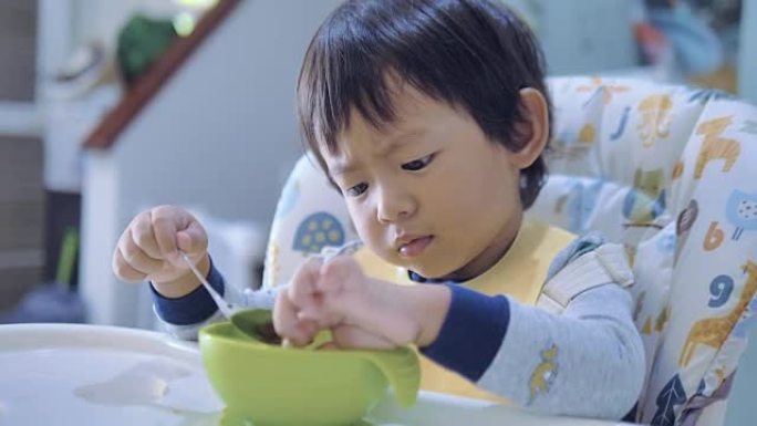 小男孩在高脚椅上吃婴儿食品。