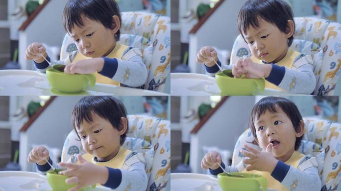小男孩在高脚椅上吃婴儿食品。